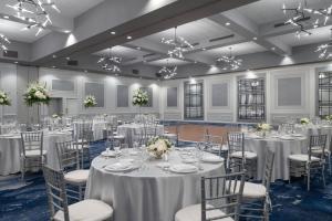 un salón de banquetes con mesas y sillas blancas en Sheraton Framingham Hotel & Conference Center, en Framingham