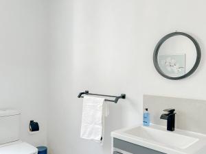 bagno con lavandino bianco e specchio di Amoris Guesthouse - In Brooklyn a Pretoria