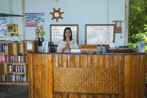 a woman is standing behind a wooden counter at Kradan Beach Resort in Koh Kradan