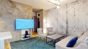 a living room with a tv on a stone wall at Grand Apartments Hrebienok in Vysoke Tatry - Stary Smokovec