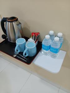 a tray with water bottles and cups on a counter at NURUL ROOMSTAY LANGKAWI in Pantai Cenang
