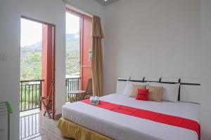 a bedroom with a large bed and a balcony at RedDoorz Syariah near Gerbang Dieng 2 in Dieng