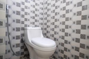 a bathroom with a white toilet in a tile wall at RedDoorz Syariah near Gerbang Dieng 2 in Dieng