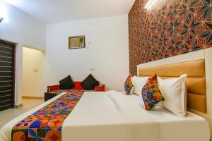 新德里的住宿－FabExpress Gross Plaza，卧室配有一张带彩色枕头的大型白色床。