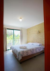 a bedroom with a bed and a large window at Coolum Budget Accommodation in Coolum Beach