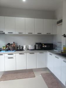 a white kitchen with white cabinets and appliances at 88house suratthani in Suratthani