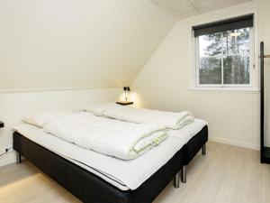 a bedroom with a bed with white sheets and a window at Holiday home Læsø II in Læsø