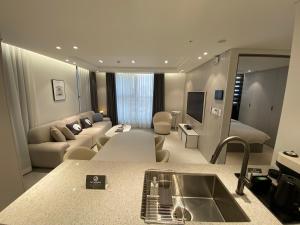uma cozinha e sala de estar com um sofá e um lavatório em HOTEL THE DESIGNERS LYJ SUITE YEOKSAM em Seul