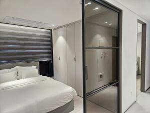 ソウルにあるHOTEL THE DESIGNERS LYJ SUITE YEOKSAMのベッドルーム1室(ベッド1台付)、スライド式ガラスドアが備わります。