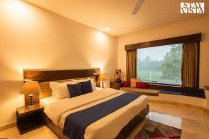 a bedroom with a large bed and a window at StayVista's Casba Farm Retreat - Pet-Friendly Villa with Rooftop Lounge, Outdoor Pool, Lawn & Bar in Chandīgarh