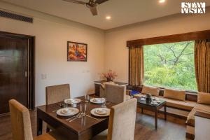 comedor con mesa y sofá en StayVista's Casba Farm Retreat - Pet-Friendly Villa with Rooftop Lounge, Outdoor Pool, Lawn & Bar, en Chandīgarh