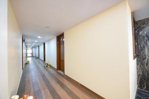 pusty korytarz z białymi ścianami i drewnianą podłogą w obiekcie FabHotel Mona International w Nowym Delhi