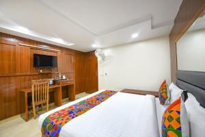 a bedroom with a bed and a desk and a television at FabHotel Mona International in New Delhi