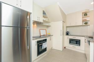 a kitchen with a stainless steel refrigerator and white cabinets at Granite Views Beachfront Apartment + WiFi in Encounter Bay