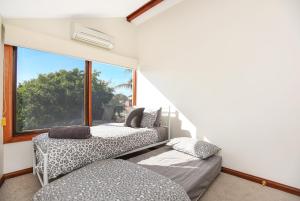 two beds in a room with a large window at Granite Views Beachfront Apartment + WiFi in Encounter Bay