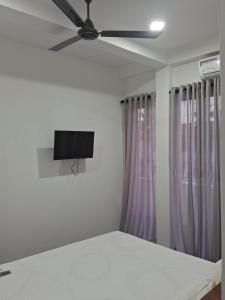 um quarto com uma ventoinha de tecto e cortinas roxas em RKO Villa27 em Habaraduwa Central