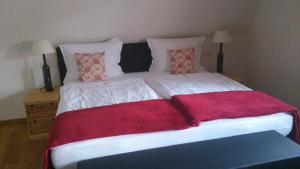 a large white bed with red sheets and pillows at Landgasthof Zum Hasen in Kleinwallstadt