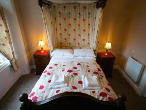 The Station Hotel Penrith في بنريث: غرفة نوم مع سرير مع زهور حمراء عليه