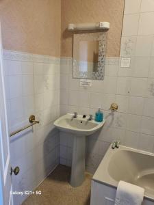 a bathroom with a sink and a bath tub at The Station Hotel Penrith in Penrith