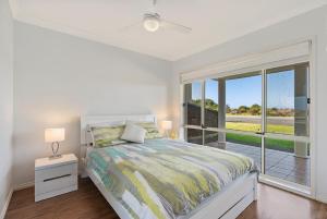 a white bedroom with a bed and a large window at Esplanade Beachfront Victor Harbor in Victor Harbor