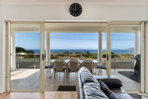 a living room with a table and a clock on the wall at Esplanade Beachfront Victor Harbor in Victor Harbor