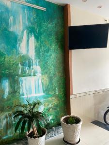 a painting of a waterfall on a wall with two plants at Nhà Nghỉ 529 in Vung Tau