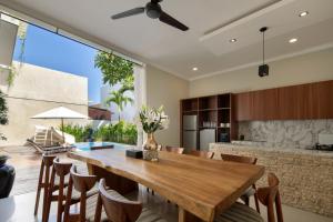 cocina y comedor con mesa de madera y sillas en Daha Mansions Seminyak, en Seminyak