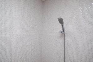 una doccia in un angolo con una parete di piastrelle bianche di RedDoorz Apartment near Exit Toll Colomadu a Solo Altre 37 foto
