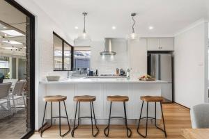 a kitchen with two bar stools and a counter at Sea La Vie ~ Pet Friendly Coastal Chic Broadwater Retreat in Broadwater +28 photos