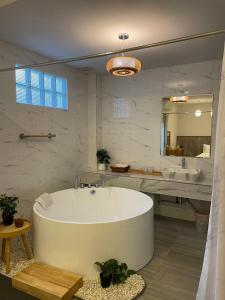 a large white bathroom with a tub and a sink at Nan Cozy House in Nan