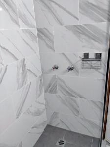 een wit betegelde badkamer met witte muren bij Sandstock Motor Inn Armidale in Armidale