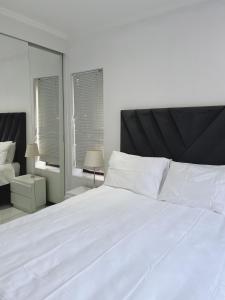 a bedroom with a large white bed and a mirror at Place to remember in Sandton