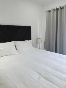 a white bed with a black headboard and white pillows at Place to remember in Sandton