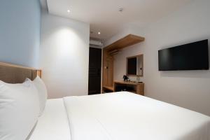 a bedroom with a white bed and a flat screen tv at Haven Hut Riverside Hotel in Ho Chi Minh City