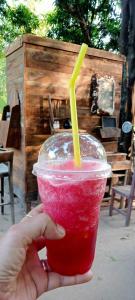 a person holding a red drink with a yellow straw at สามชุกบ้านสวน in Sam Chuk
