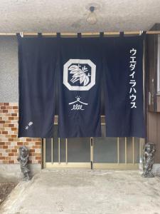 um portão com uma cortina azul e um sinal em みんなでつくるふるさとウエダイラハウス 