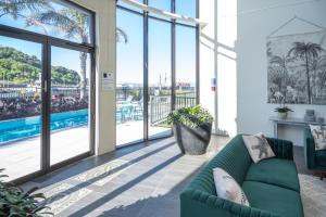 a living room with a green couch and large windows at Portside Hotel Gisborne in Gisborne