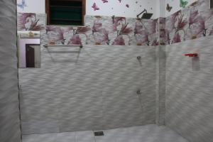 box doccia in bagno con fiori rosa sul muro di Diamond Cottage a Habaraduwa Central