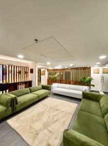 a living room with green couches and a rug at The Habitat Suites in Guruvāyūr