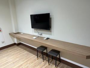 a desk with two stools and a television on a wall at 五星佶民宿 in Jinning