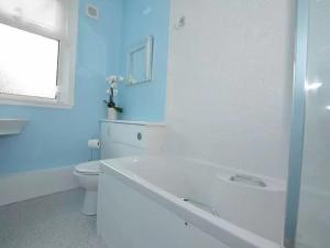 a bathroom with a tub and a toilet and a window at Criffel View in Dumfries