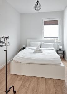 - une chambre blanche avec un grand lit blanc et une fenêtre dans l'établissement 10th Floor Unii Lubelskiej Apartment, à Poznań