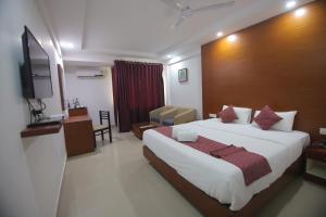 um quarto de hotel com uma cama e uma televisão em Nakshatra Emerald em Guruvayur