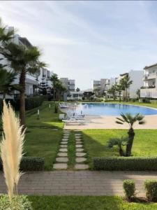 a resort yard with a swimming pool and palm trees at Blanca Beach in Sidi Rahal