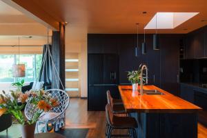 a kitchen with black cabinets and a wooden counter top at Te Tupahipahi - The Sandspit in Nelson