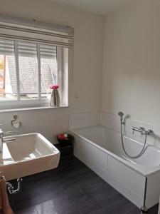 a white bathroom with a tub and a sink at NEU! Schicke und moderne FeWo Lindenalle OG in Hanstedt