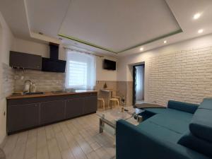 a living room with a blue couch and a kitchen at Apart Invest Dworcowa 1 i 2 in Szklarska Poręba