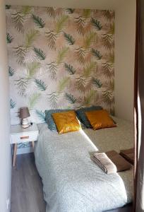 um quarto com uma cama com uma parede com palmeiras em Les Studio Cosy - Lunéville centre em Lunéville