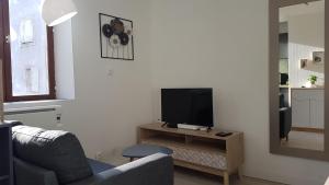 a living room with a couch and a television on a table at Le Rêve bleu - Studio Lunéville centre in Lunéville