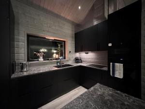 eine Küche mit schwarzen Schränken, einem Waschbecken und einem Fenster in der Unterkunft Vinterdröm Idre Himmelfjäll in Idre